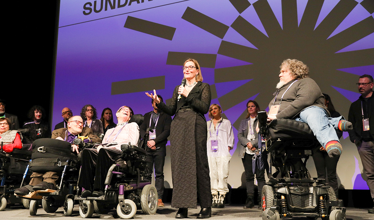 The cast and crew of Crip Camp take the stage at the Sundance Film Festival. That’s co-director Nicole Newnham holding the mic.