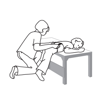 A drawing of a caretaker using a table to teach a client standing skills while adjusting clothing for toileting
