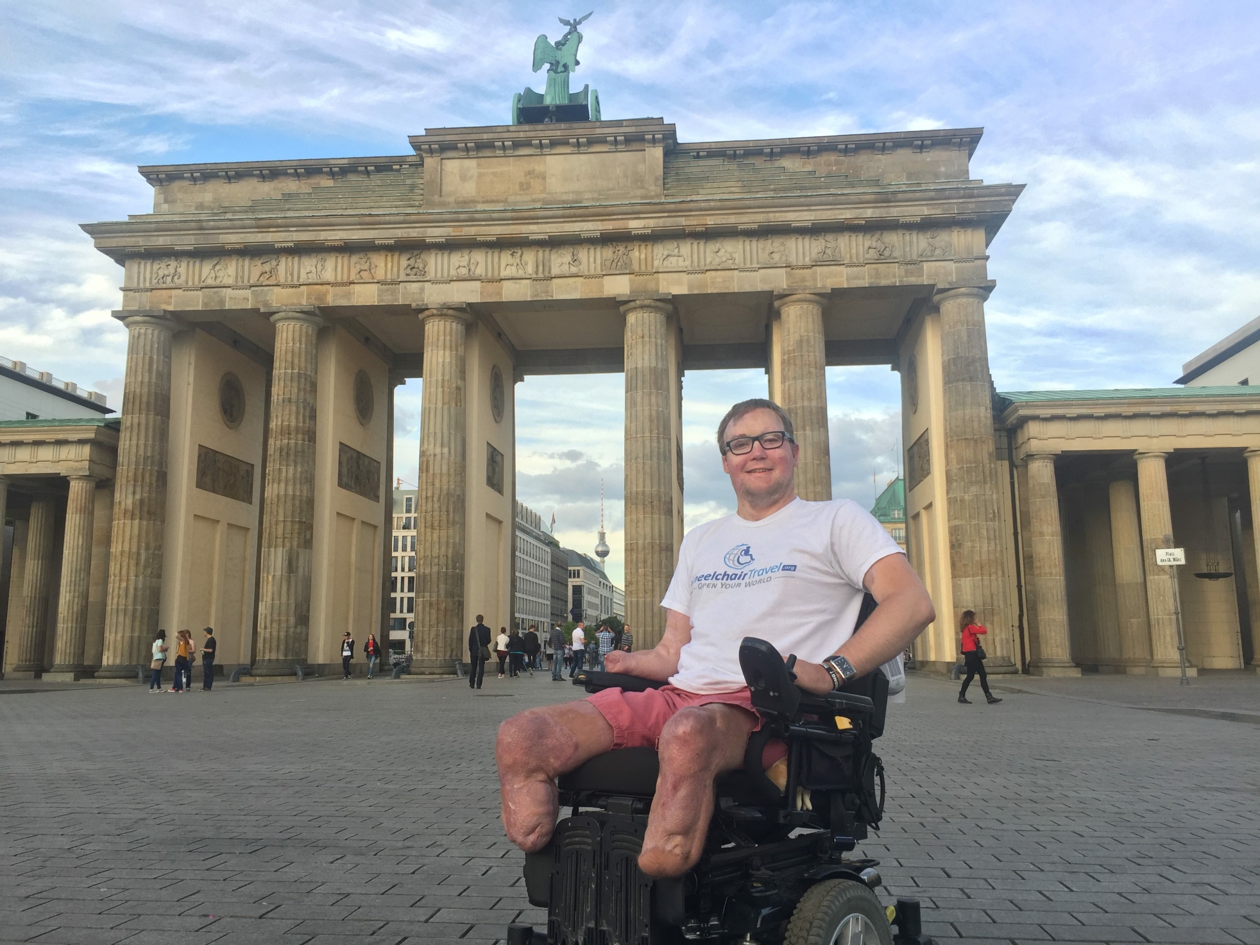 power wheelchair user shown smiling in front of monument